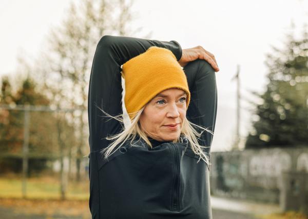 A woman stretches her arms outside before her workout.