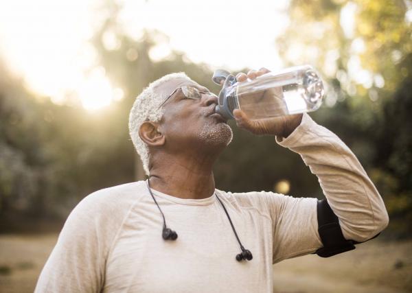An older man takes a swig of water from his water bottle while enjoying the outdoors.