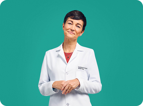 A pharmacist looks at the camera in her lab coat.