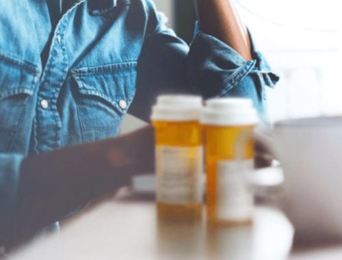 Person with prescription medication bottles on a table