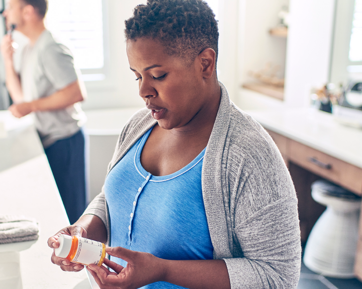 Woman looks at the label on a prescription.