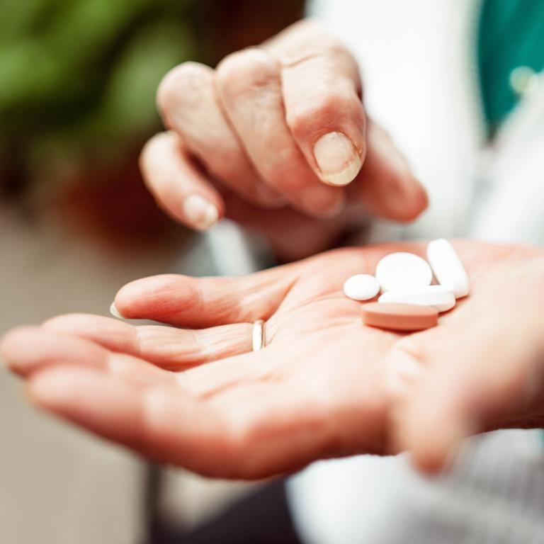 A woman holds pills in her hand.