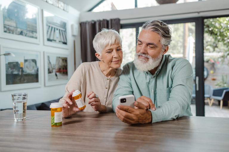 A man and woman sit together to review their prescription medications and coverage