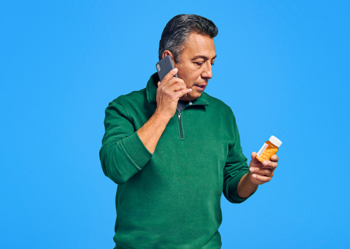 Man on his phone looking at pill bottle blue background