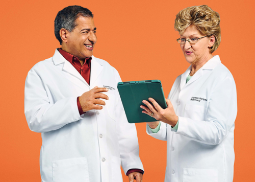 Two pharmacists consulting each other orange background