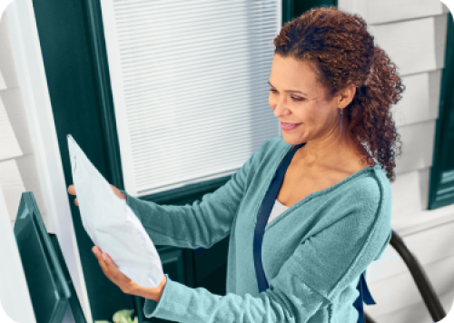 A woman reviews her home delivery order ask she picks up her mail
